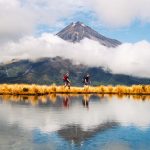 Hiker Heterosexual couple Reflection of Mount Taranaki Egmont in natural lake