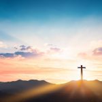 Silhouette cross on mountain sunset background