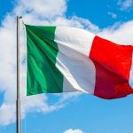 National flag of Italy waving into blue sky