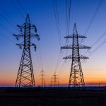 High voltage power line in field at sunset
