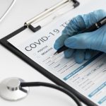 close-up-doctor-completing-covid-medical-form