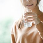 Happy woman drinking water while smiling, copy space.
