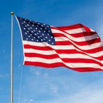 American Flag waving in the wind, with beautiful red white and blue colors.