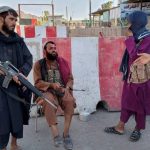 Taliban fighters stand guard at a check point in Farah