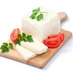 White Bulgarian cheese, arranged with tomatoes and parsley on cutting board