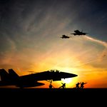 Military aircraft before take-off from aircraft carrier on sunset background