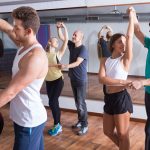 Young sporty girls and men learning latino steps