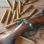 Hunting gun with bullets on old wooden background