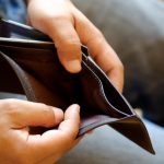 Man looking at his empty leather wallet in office.